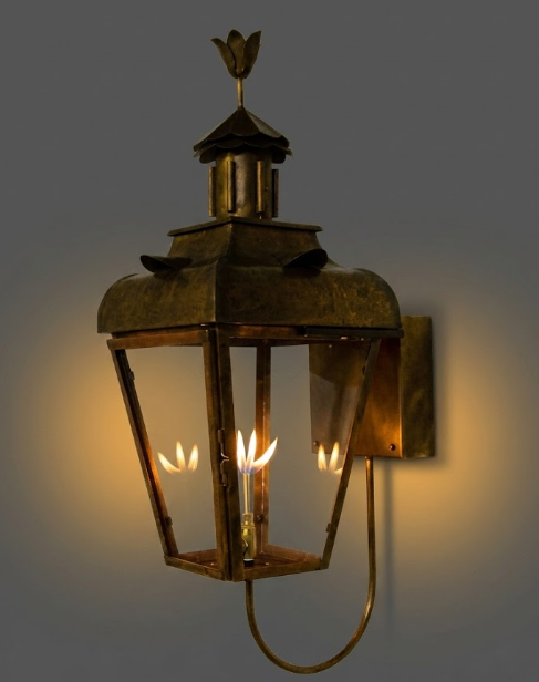 Decorative wall-mounted entryway lantern with a warm glow on a dark background
