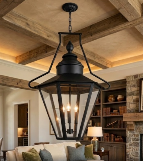 Black pendant light hanging in a living room with wooden beams and a stone fireplace.