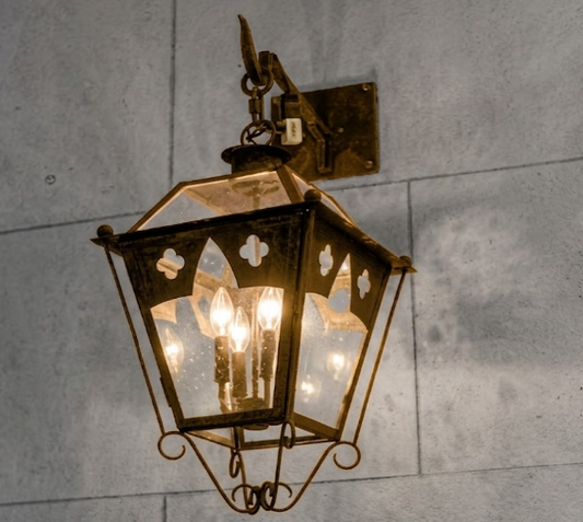 Decorative wall-mounted lantern with glass panels on a stone wall.