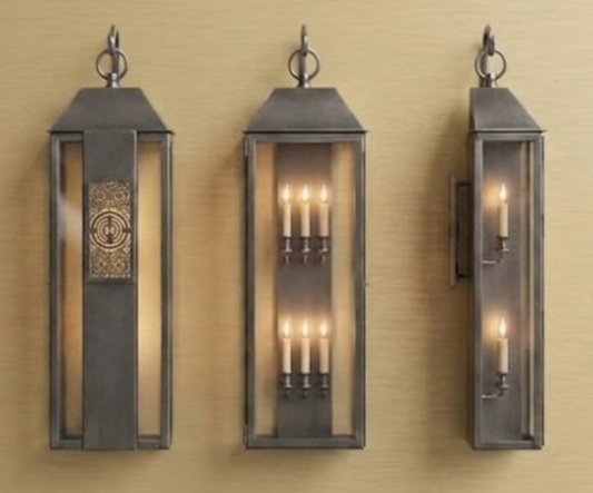 Three wall-mounted lanterns with candle-like lights on a beige wall.