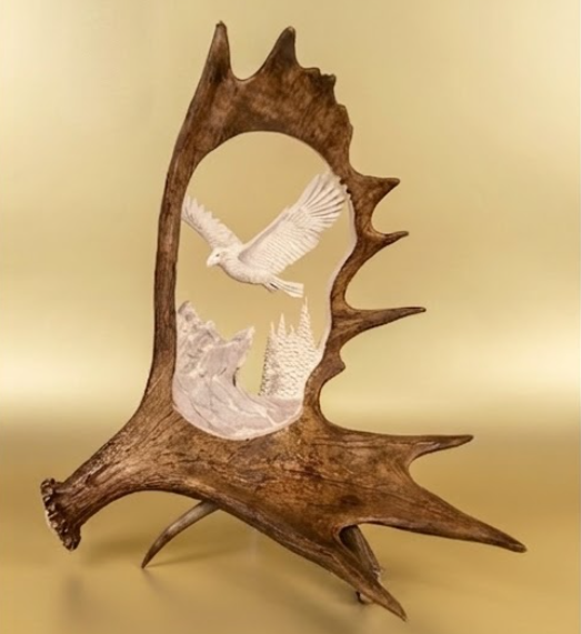 Decorative antler with a white dove and mountain design on a beige background