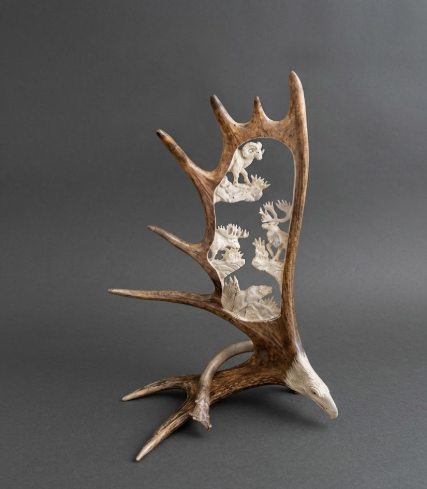 Decorative antler with embedded figurines on a gray background