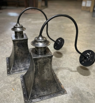 Two Copper wall sconce metal lamp fixtures on a concrete floor