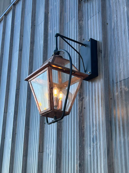 Raw copper foyer entryway kitchen island pendant light fixture with three visible bulbs on a dark background