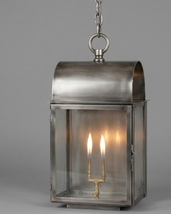 Silver copper pendant light lantern with two lit candles inside on a gray background