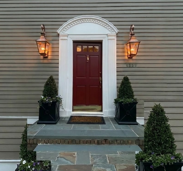 Front door of a house with decorative elements and entryway lighting fixtures.