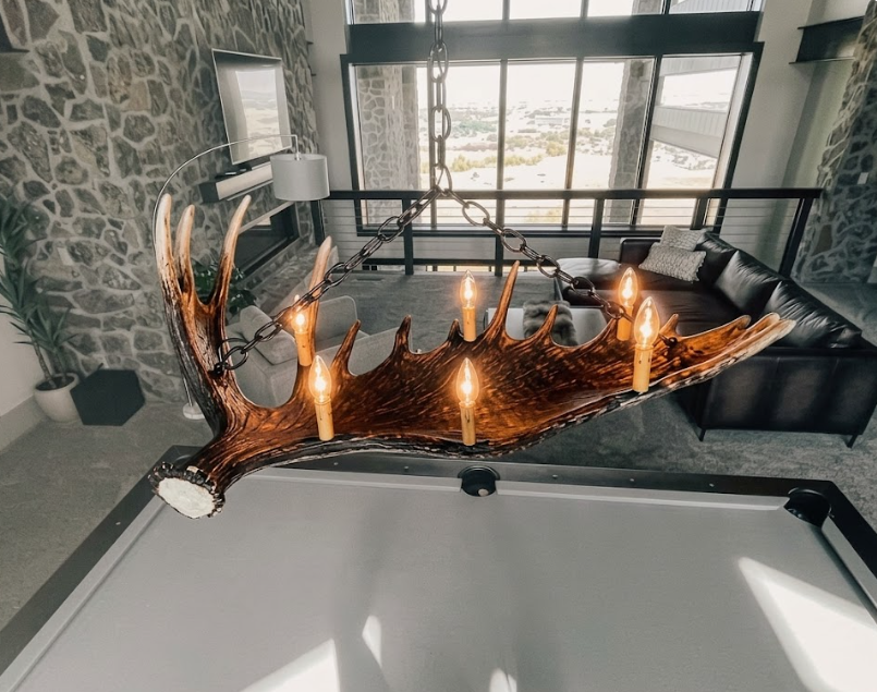 Modern living room with a large Faux moose antler-style chandelier over a pool table.