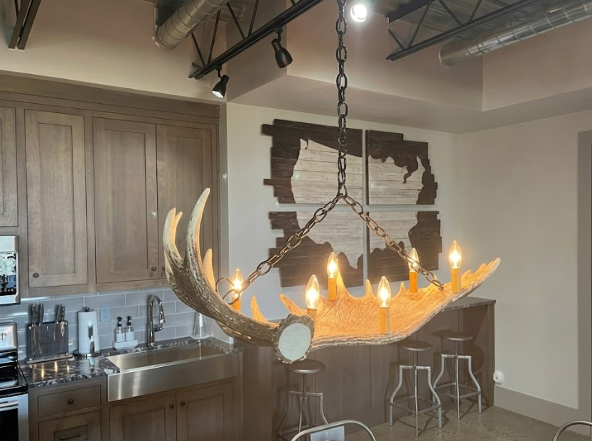 Modern kitchen with a unique Faux moose chandelier hanging above a bar area.