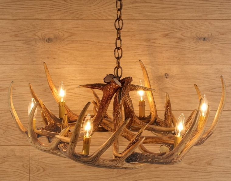 faux deer Chandelier made of antlers with lights on a wooden background