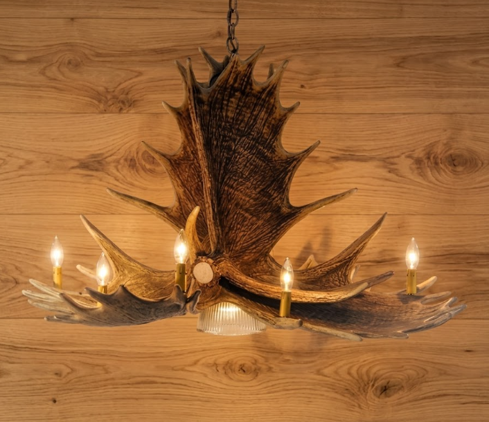 Decorative faux moose chandelier with antler design on a wooden wall