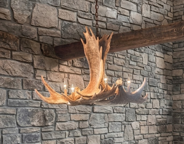 faux moose Antler chandelier hanging against a stone wall