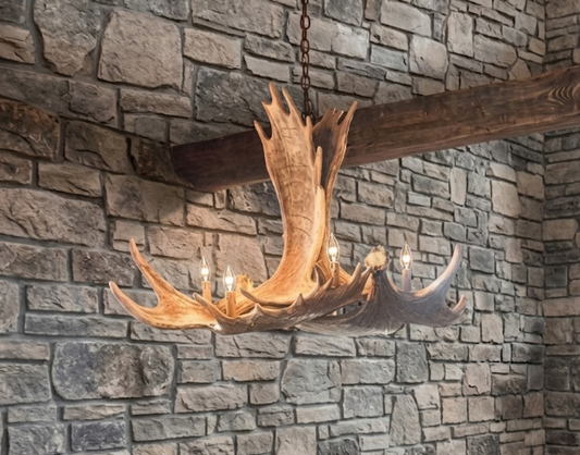 faux moose Antler chandelier hanging against a stone wall