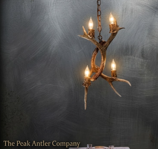 Antler chandelier with four lights on a textured gray background