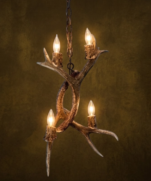 Antler chandelier with four lit lights on a dark background