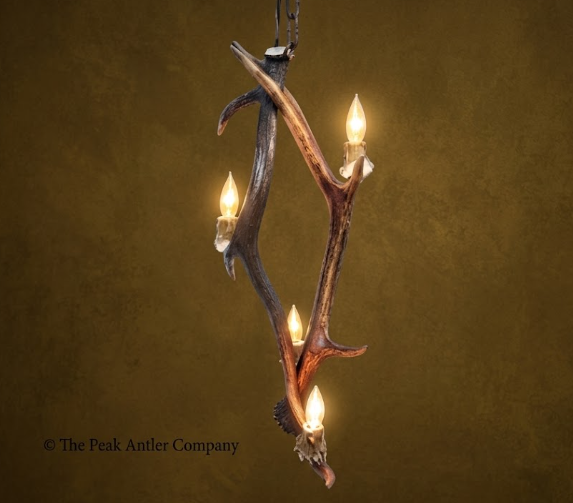 Antler chandelier with four lights on a brown background, branded 'The Peak Antler Company'.
