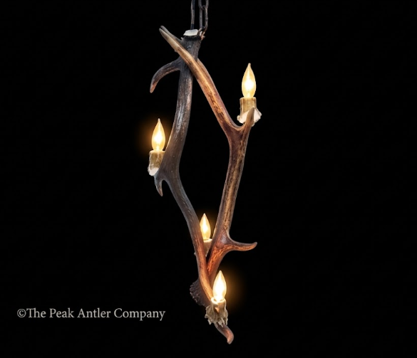 Antler chandelier with four lights on a black background, branded 'The Peak Antler Company'.