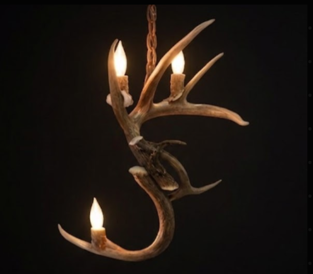 Antler chandelier with three candles on a black background