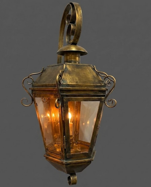 Vintage-style brass outdoor wall gas light fixture on a dark background