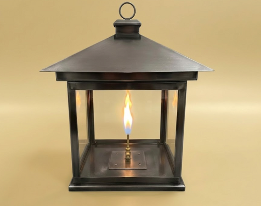 Decorative pendant lantern with a lit candle inside on a beige background