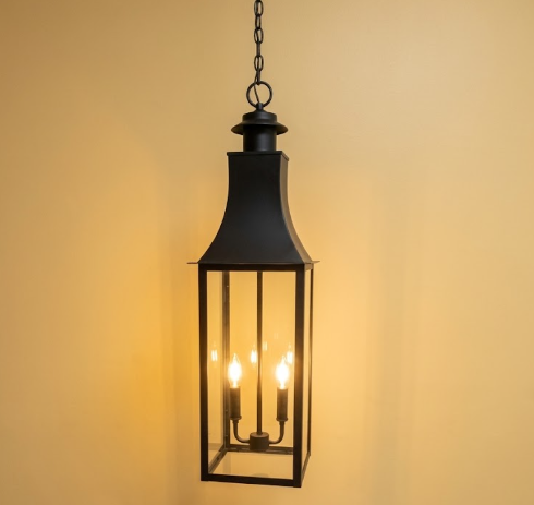 Black hanging kitchen island pendant lantern with three lights on a warm yellow background
