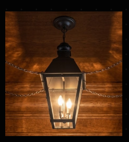 Vintage-style hanging pendant light electric lantern with two lit bulbs against a wooden background in a dark room