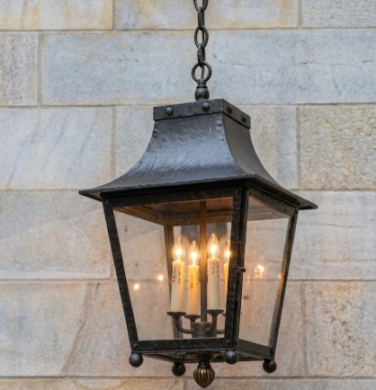 Decorative outdoor pendant foyer lantern hanging against a stone wall.