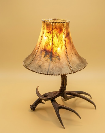 Decorative lamp with antler base and textured glass shade on a beige background