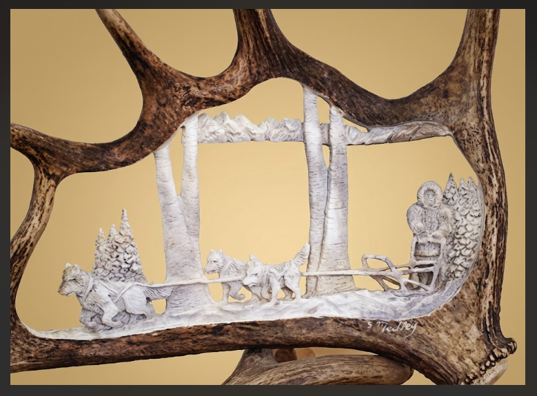 Decorative piece with carvings of people and animals on an antler frame