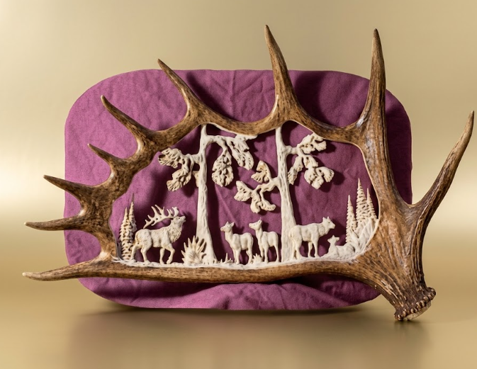 Decorative wall art with deer antlers and cut-out deer figures on a purple background