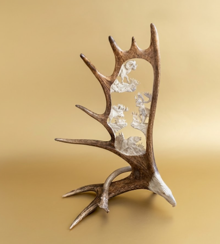 Decorative antler with embedded figurines on a beige background