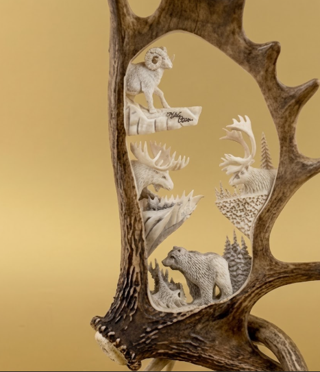 Carved deer antler with animal figures on a gold background