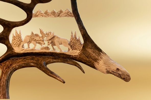 handcrafted antler carving of two moose fighting on a hand crafted moose antler with an eagles head at the base.