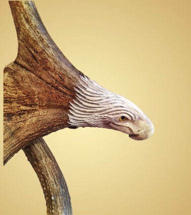Eagles head on the base of a moose antler carving with a tan background.  