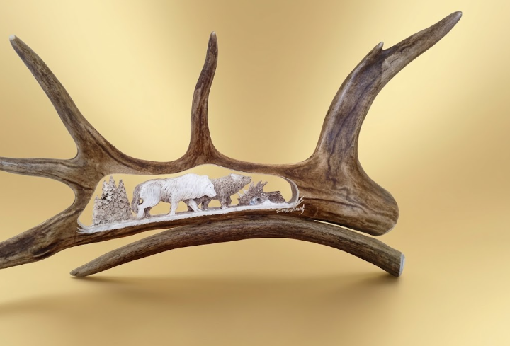 Small  carving of two wolves on the chase for food with a tan background.