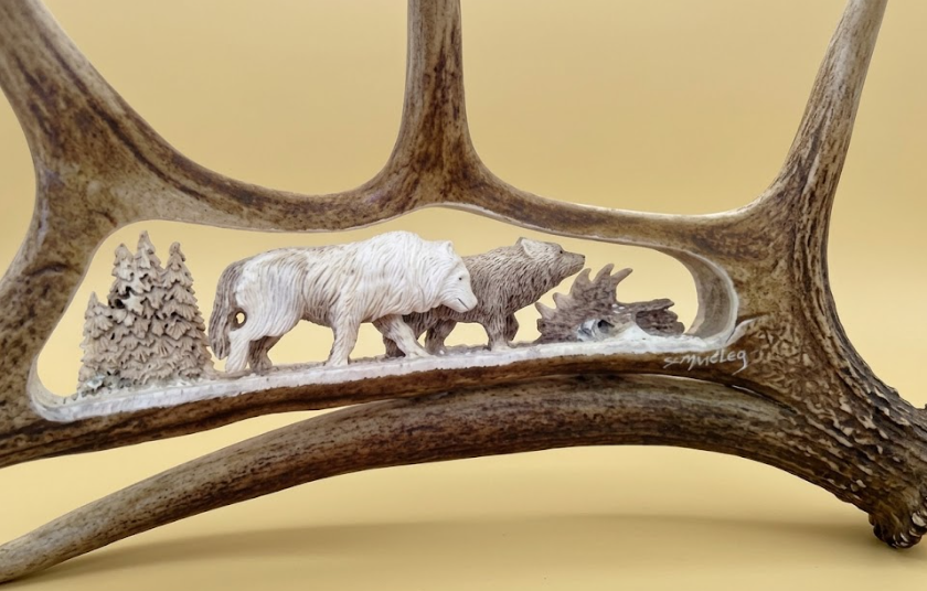 Carved  antler with two wolves and a tree on a beige background