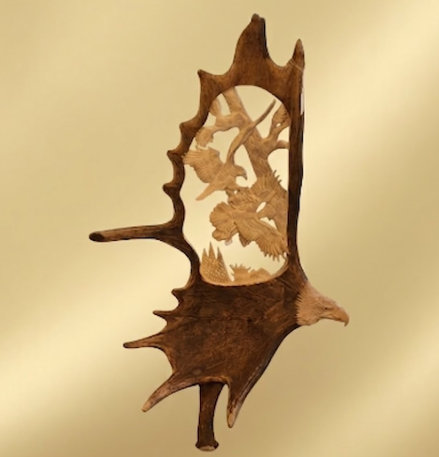 Eagle moose antler carving depicting two fighting eagles soaring above the trees