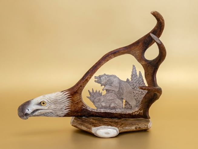 Decorative item with an eagle head and carved bear inside on a beige background