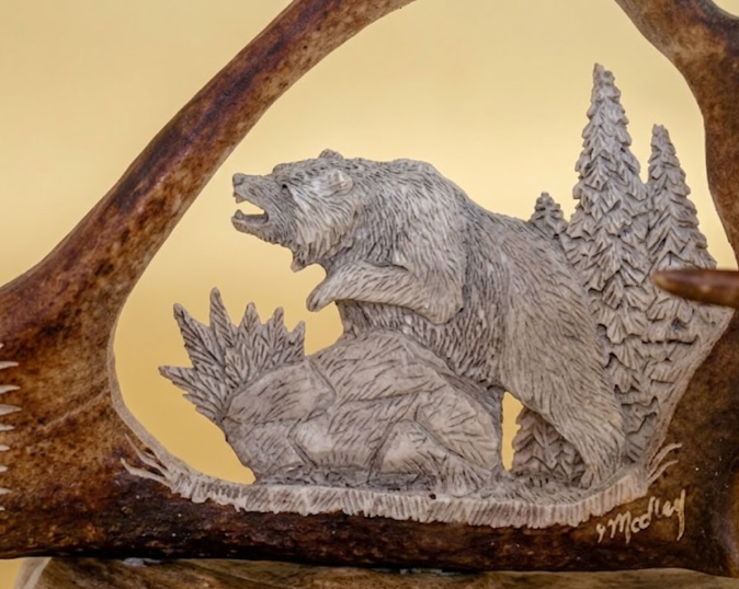 Carved bear and antler design on an antler surface