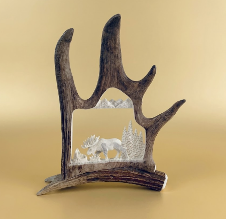 Decorative caribou antler shed with a miniature scene of a moose and trees on a beige background