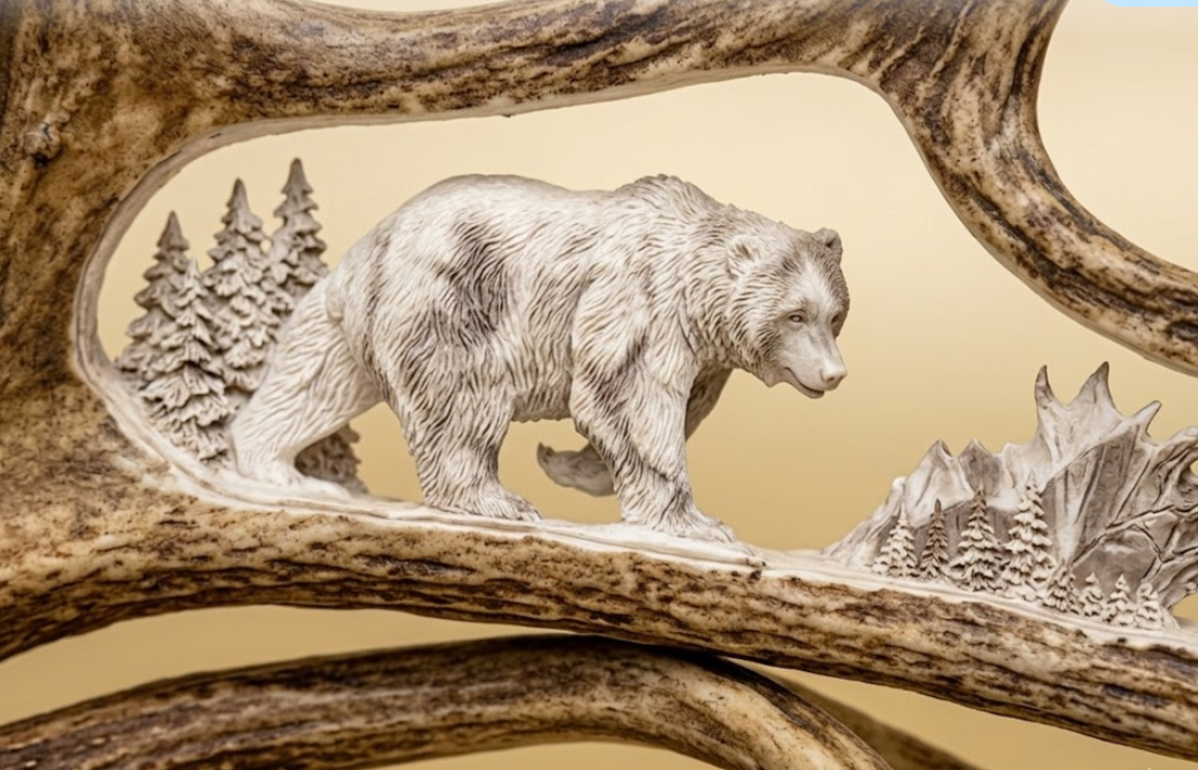 Carved bear on a moose antler with a forest background