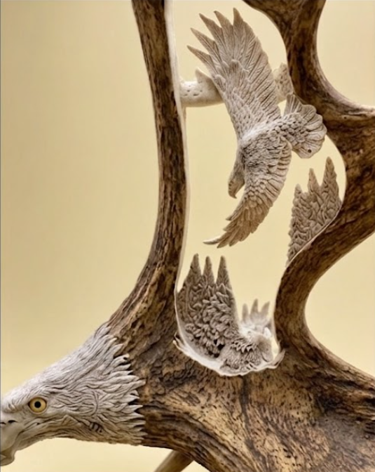 Decorative moose antler wall or table art of a bald eagle soaring among the trees, with a beige background