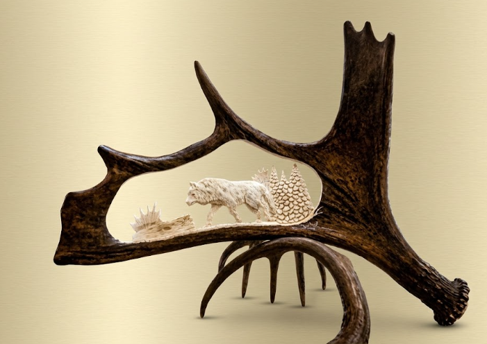 Intensely focused wolf in a forest, hand crafted on a Moose antler on a tan background.
