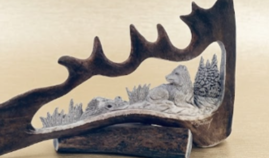 Antler with a carved napping wolf landscape inside on a beige background
