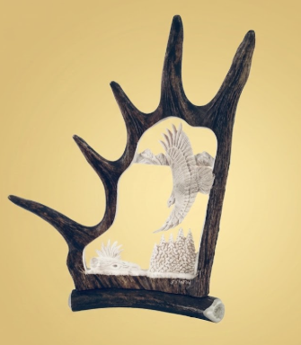 Decorative wall art, a carved moose antler and a silhouette of an eagle soaring, on a beige background