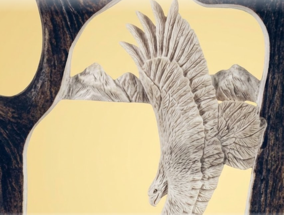 Eagle antler carving on a moose antler against a tan background.