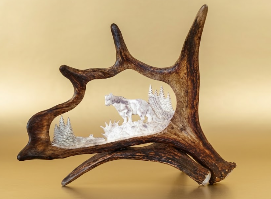 Moose antler hand crafted mountain lion antler carving, desk mount against a tan background.
