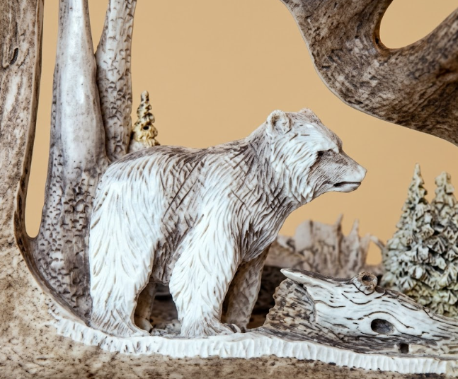 Carved bear figure in a natural setting with trees and rocks hand carved Moose antler with eagles head desk mounted.