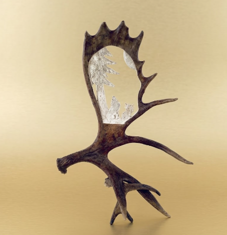 Moose antler table stand, howling wolf antler carving on a tan background.