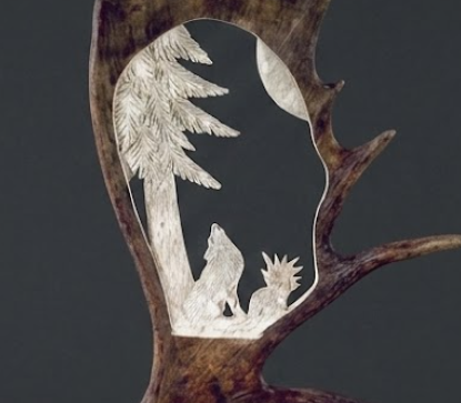 Moose antler carving of wolf howling at the moon, sitting under a big tree.
