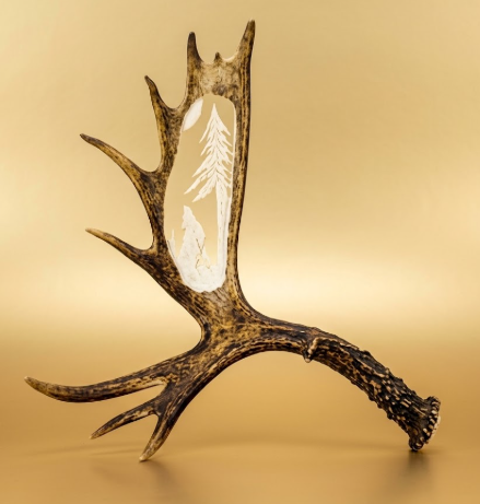 wall hanging wolf cut from a moose antler.  Wolf is howling at the moon. tan background.